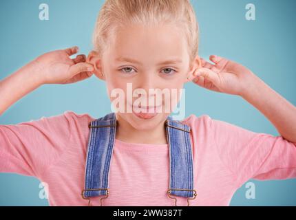 Child, portrait and funny face in studio for humor on blue background with silly mood, mockup space or happiness. Female person, girl and tongue out Stock Photo