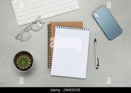 Flat lay composition with notebooks, smartphone, glasses and pen on light grey table Stock Photo