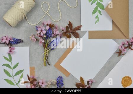 White paper with place to fill in with content, little blue and pink flowers and envelopes on a table. Stock Photo