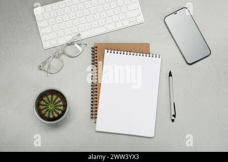 Flat lay composition with notebooks, smartphone, glasses and pen on light grey table Stock Photo