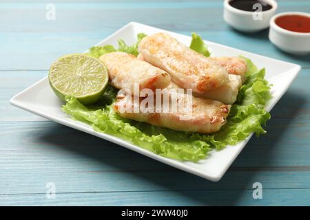 Delicious fried spring rolls on light blue wooden table Stock Photo