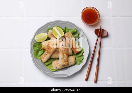 Tasty fried spring rolls served on white tiled table, flat lay Stock Photo