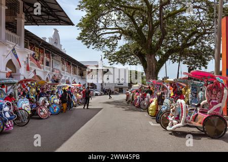 Trishaws, or cycle rikshaws, decorated with popular film and cartoon characters and waiting to transport tourists in Malacca, Malaysia Stock Photo