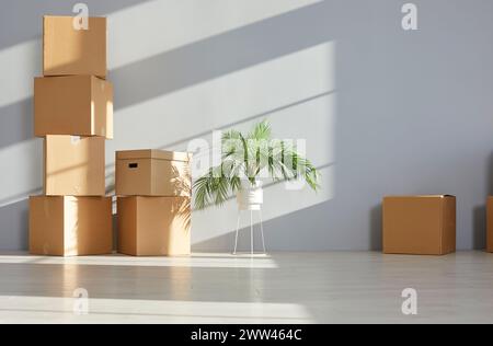 Pile of cardboard boxes are stacked against the wall in an empty room in new apartment. Stock Photo