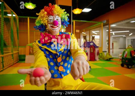 Portrait of funny clown showing tricks with red foam nose making surprise Stock Photo