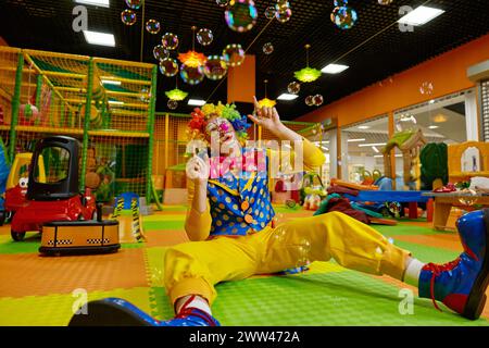 Funny clown performing soap bubbles show for kids at kid center Stock Photo