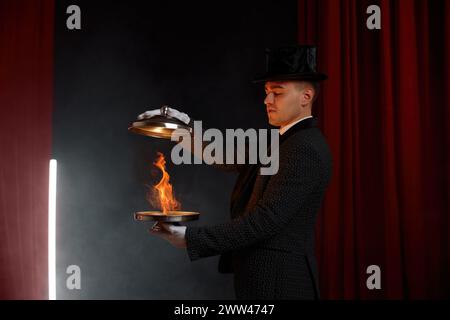 Male magician showing trick with magic fire illusion with steel tray Stock Photo