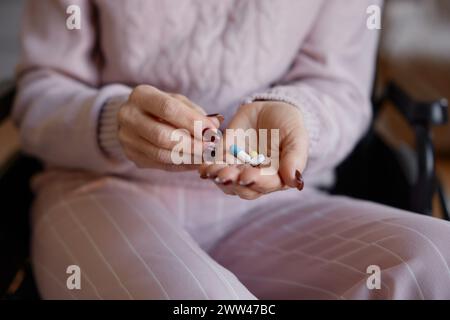 Closeup of old woman in wheelchair taking prescribed pills Stock Photo