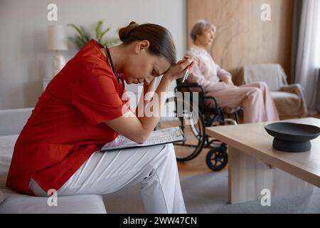 Upset frustrated doctor holding head leaned over patient card Stock Photo