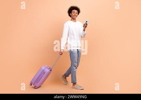 Full length photo of positive man wear trendy clothes walk gps navigation search hotel address location isolated on beige color background Stock Photo