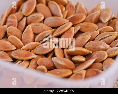 A close-up shot of pumpkin seeds in a plastic container. Stock Photo