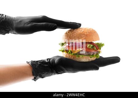 Hands in black gloves hold a juicy, appetizing beef burger on a white background. Hamburger in hands isolated. Banner, fast food advertising. Stock Photo