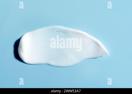 Texture of white cream on blue background. Smear swatch of moisturizer close up.  Beauty skin care gel product smear smudge. Sunblock cream sample on Stock Photo