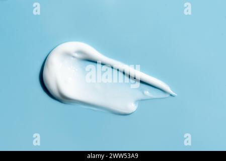 Texture of white cream on blue background. Smear swatch of moisturizer close up.  Beauty skin care gel product smear smudge. Sunblock cream sample on Stock Photo