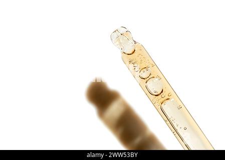 Golden bubble vitamin oil or retinol serum isolated on white background with laboratory glass pipette. Beauty and skincare, bio science concept. Stock Photo