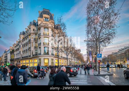 Crowds stroll by Zara at the Champs-Élysées and Berri corner as evening falls in Paris. Stock Photo