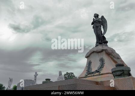094 Sword-bearing angel and other statues peeking over graves on Avenida Cristobal Colon Avenue west side, Cementerio de Colon Cemetery. Havana-Cuba. Stock Photo