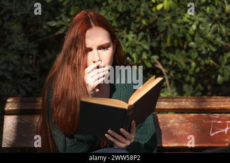 Woman reading such an interesting book and making gestures with her face of intrigue or amazement Stock Photo