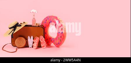 Suitcase and beach accessories on pink background with space for text. Travel concept Stock Photo