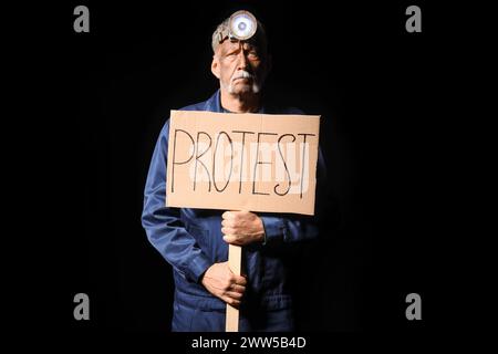 Protesting miner man with placard on black background Stock Photo