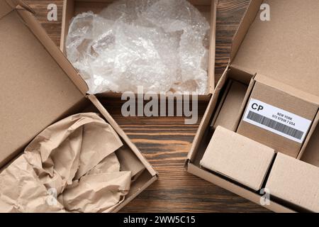 Cardboard packages with boxes, packing paper and bubble wrap on wooden table Stock Photo