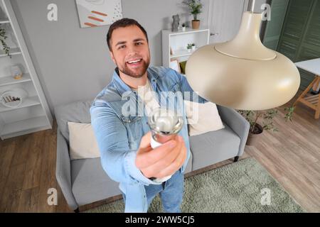 Young man changing light bulb in hanging lamp at home, closeup Stock Photo
