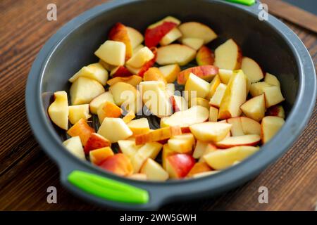 A bowl of sliced apples on a wooden table. The apples are cut into various shapes and sizes, and the bowl is filled to the brim. Concept of abundance Stock Photo