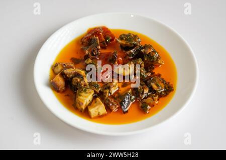 A plate of food with a red sauce and a variety of ingredients. The plate is white and the food is spread out on it Stock Photo