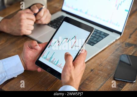 Advisor consulting stock market investor analyzing investment plan on tablet. Stock Photo