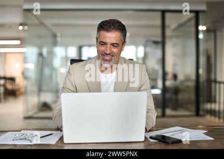 Happy middle aged professional business man using computer working at desk. Stock Photo