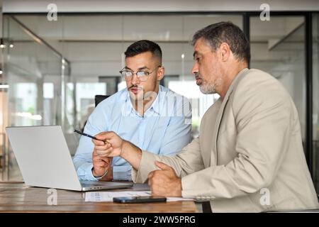 Two busy business men working using laptop computer in office. Stock Photo