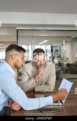Stock market traders investors working on financial chart analysis using laptop. Stock Photo