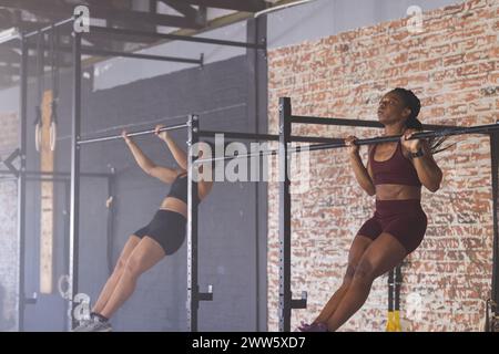 Two diverse fit women are engaged in a pull-up workout in the gym Stock Photo