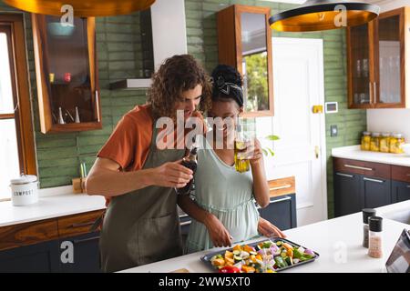 A diverse couple is preparing a salad in a modern kitchen Stock Photo