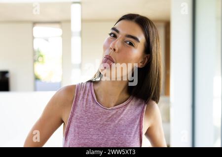 A young Caucasian brunette woman sticks her tongue out playfully at home Stock Photo