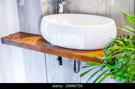 Bathroom design in loft or boho style with sink, towels and Spathiphyllum flowers in vase Stock Photo