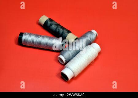 Spools of thread for working on a sewing machine lie on a red background. Stock Photo