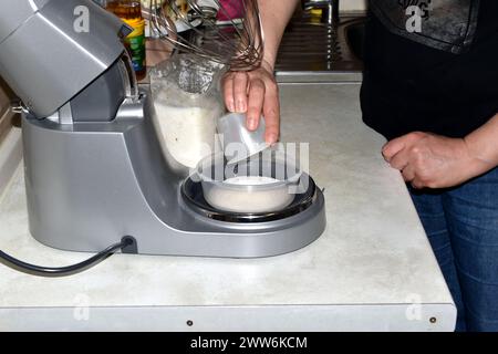 Measuring the required amount of sugar on the built-in scale in the kitchen mixer. Stock Photo