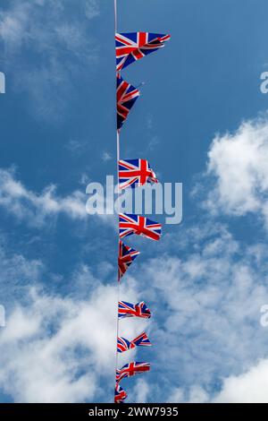 A low angle view of patriotic Union Jack bunting blowing in the wind, with a blue sky behind Stock Photo