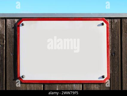 collage, enamel, metal or pottery sign on a rustic wooden wall. red frame, under a bright turquoise sky. the sun is shining, rectangular stone slab Stock Photo