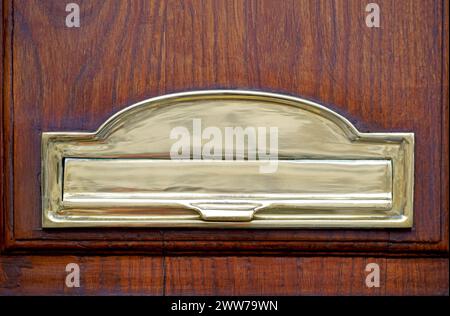 mailbox on the door. Wooden vintage door with golden postbox, letters and newspapers in mailbox. Stock Photo