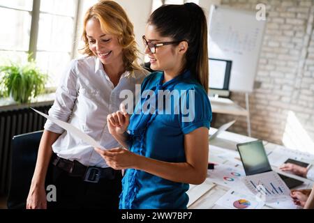 Business women entrepreneurs working in coworking space smiling, brainstorming as a team in office Stock Photo