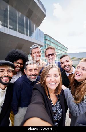 Group of multiracial business people taking a selfie together, looking at the camera smiling. Stock Photo