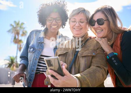 Group of multiracial middle-aged women smiling looking and using smartphone Stock Photo