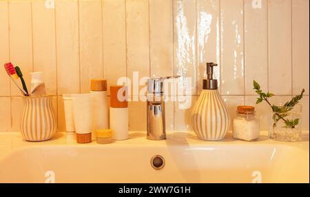 A round mirror in a wooden frame and a lamp with a wicker shade over the washbasin. A close-up of a part of the bathroom interior. A ceramic cup with Stock Photo
