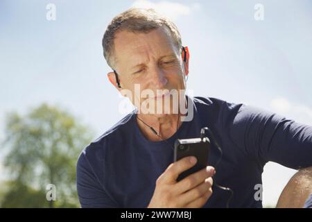 Close up of Mature Man in Park Listening to Music on Smartphone Stock Photo