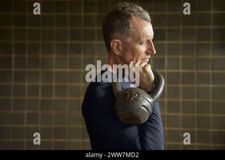 Profile of Mature Man Lifting Kettlebell Stock Photo