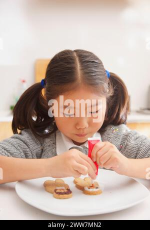 Young Girl Decorating Ginger bread man Biscuit Stock Photo