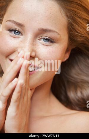 Close up of Young Woman with Hands over Mouth Smiling Stock Photo