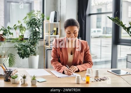 happy african american nutritionist evaluating medication while writing notes in her office Stock Photo